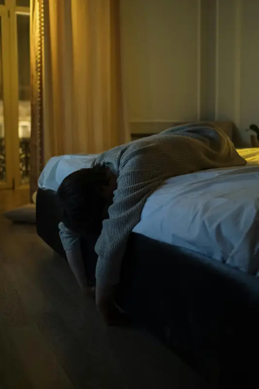 A person lying on a bed in a dimly lit room, creating a serene and tranquil atmosphere.
